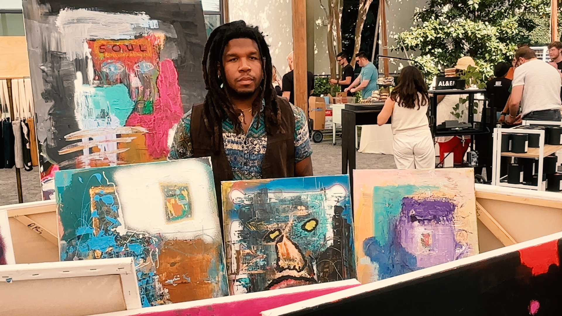 Artist standing in an area surrounded by his artwork displayed for all to see